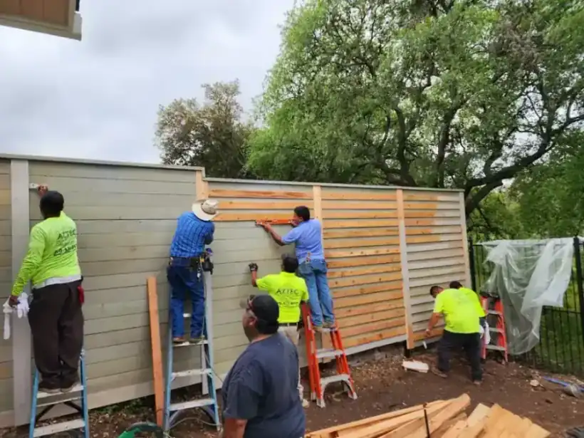 Five Aztec Fence and Ornamental Iron crew members in branded shirts installing a horizontal cedar fence