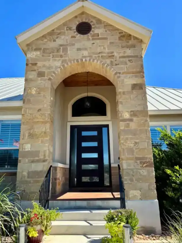 A limestone Hill Country entry with a black iron handrail built by Aztec Fence and Ornamental Iron