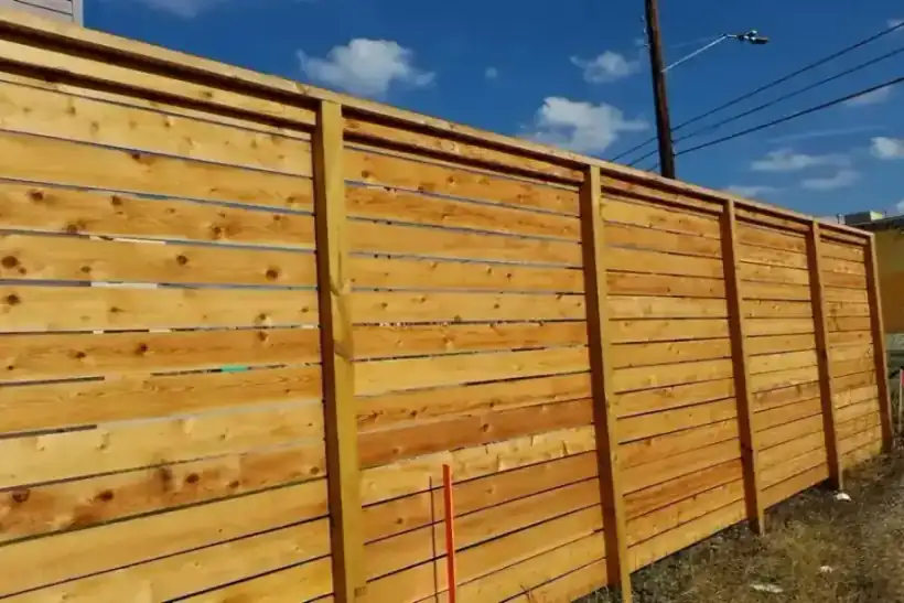 A tall horizontal cedar privacy fence on a new build