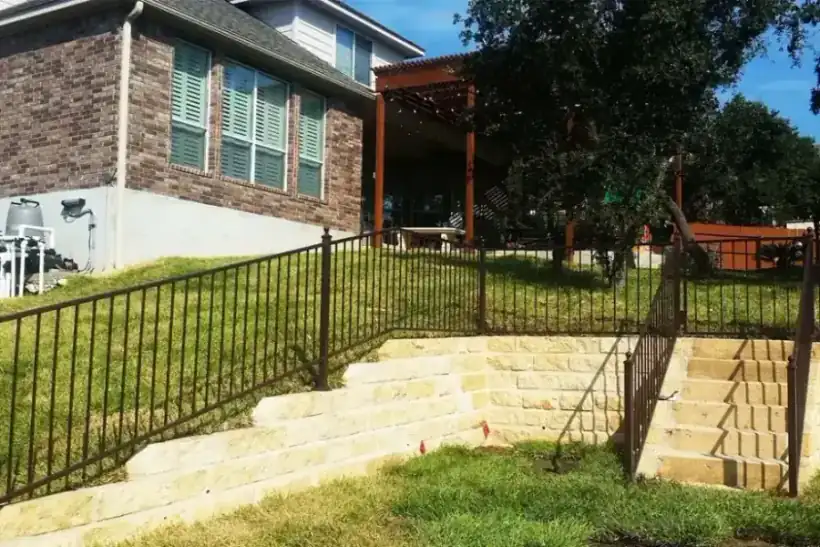 A bronze ornamental iron fence following limestone garden steps