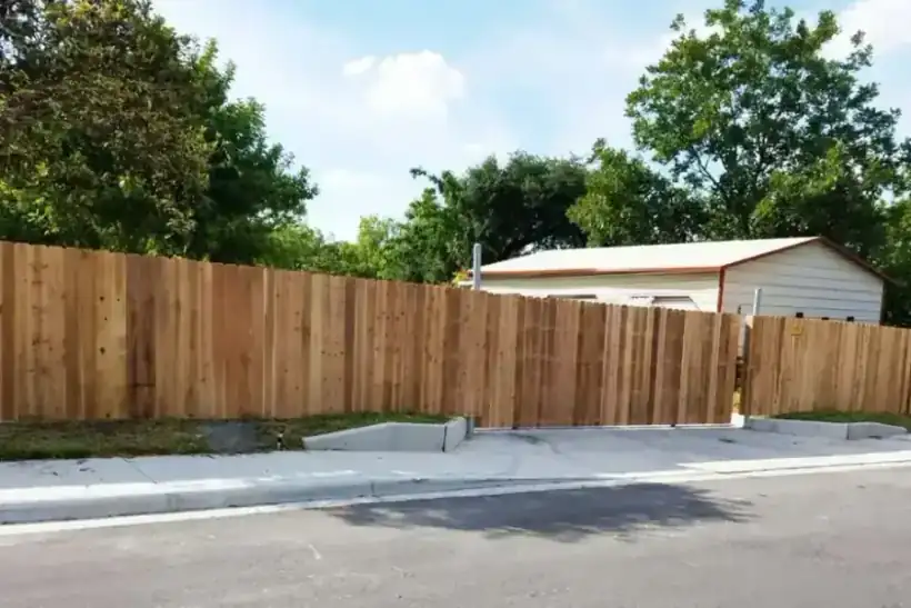 A tall cedar privacy fence with a rolling gate installed along a San Antonio street by Aztec Fence and Ornamental Iron